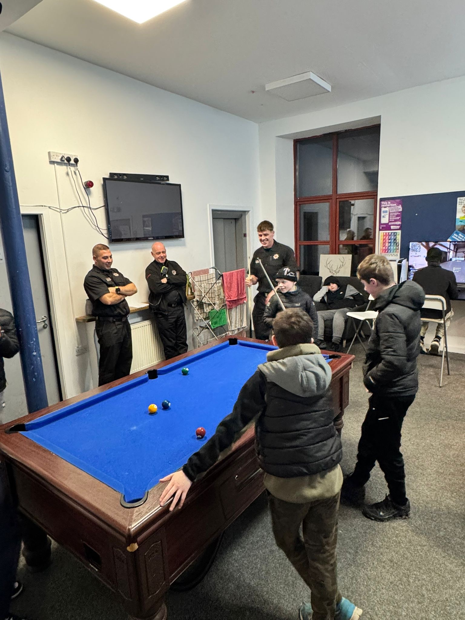 Young people and adults gathered around the pool table at TD1