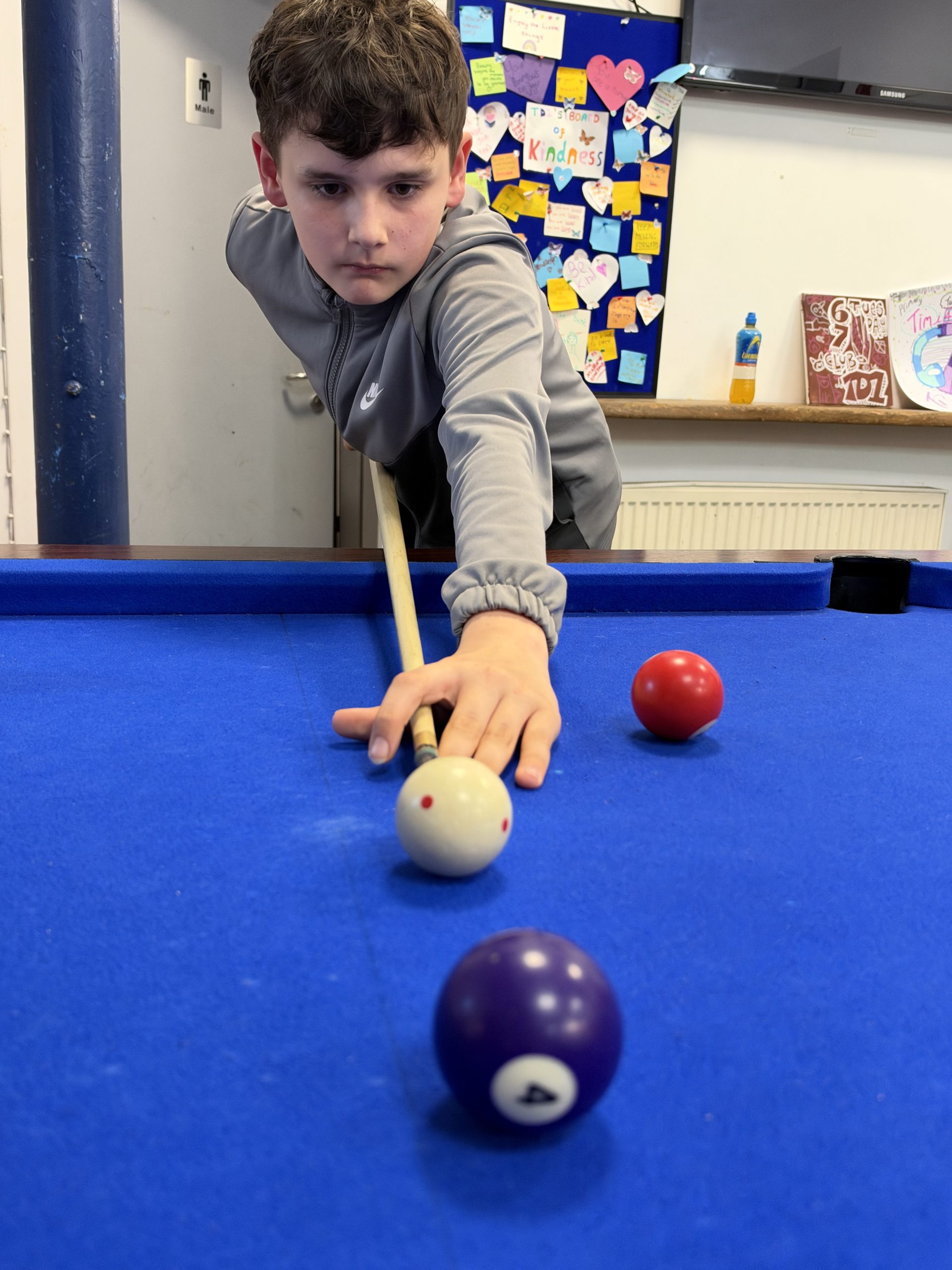 A young person lining up a shot at the pool table