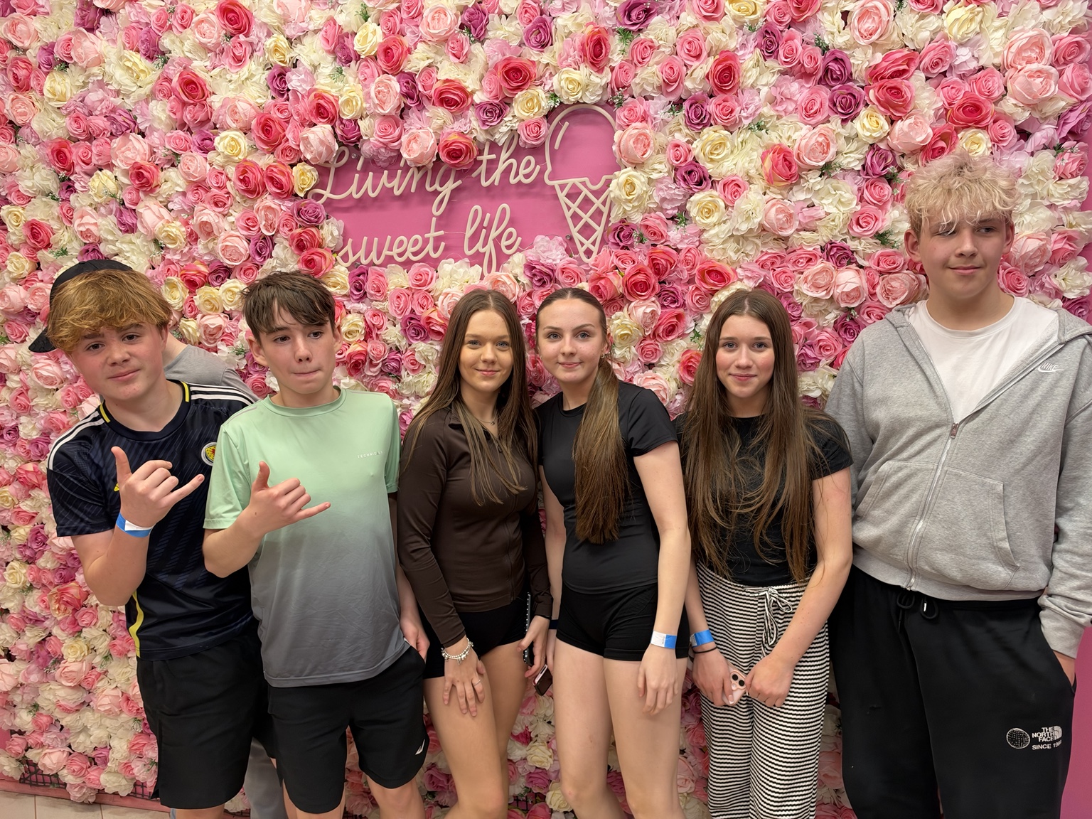 Young people together in front of a colourful floral wall