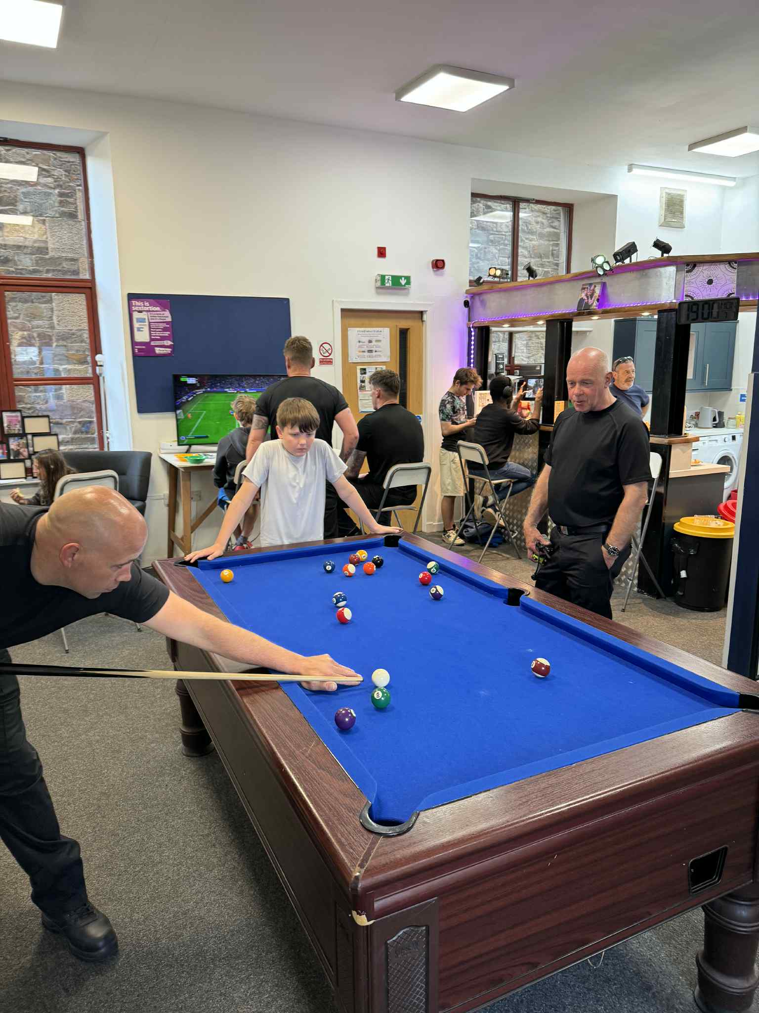 Young people and adults spending time together around the pool table at TD1